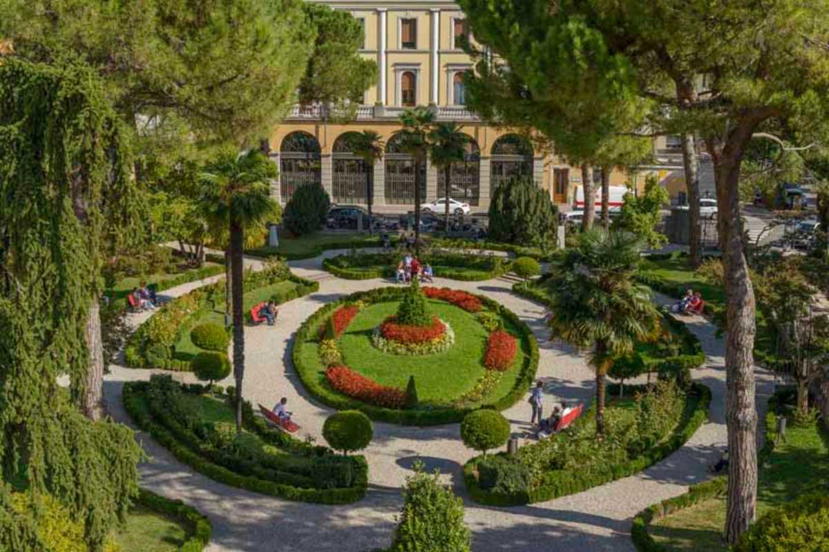 Vista di un parco a Udine durante una giornata di sole, con persone che si godono il verde