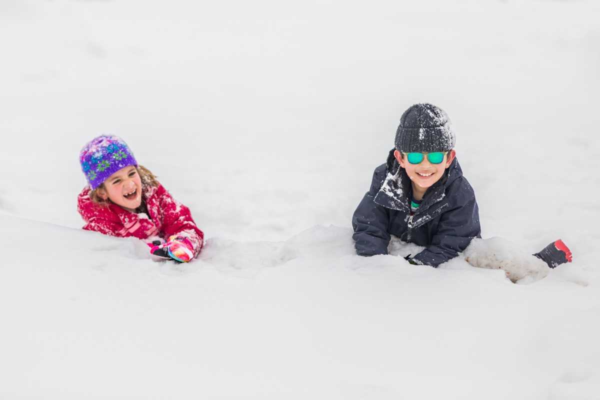Vista panoramica di Tarvisio e delle Alpi, con bambini che giocano nella neve